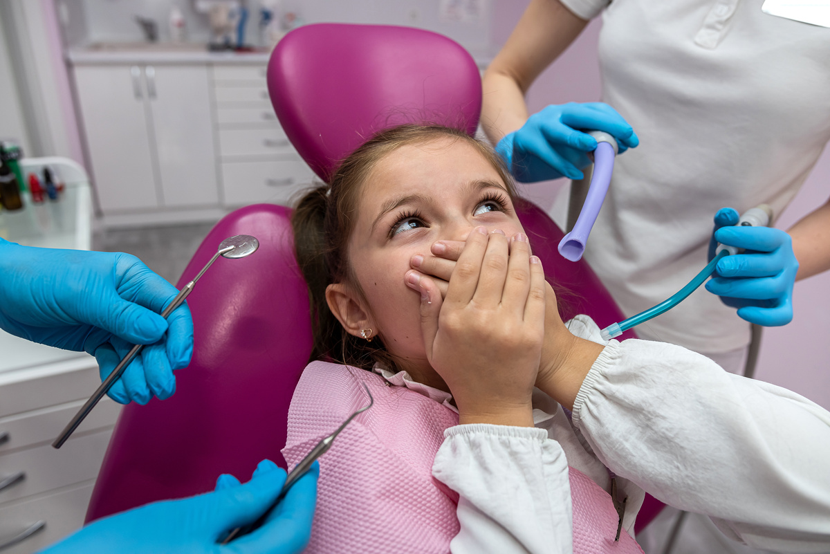 dentist is going to perform a dental examination of a frightened child in a dental clinic.