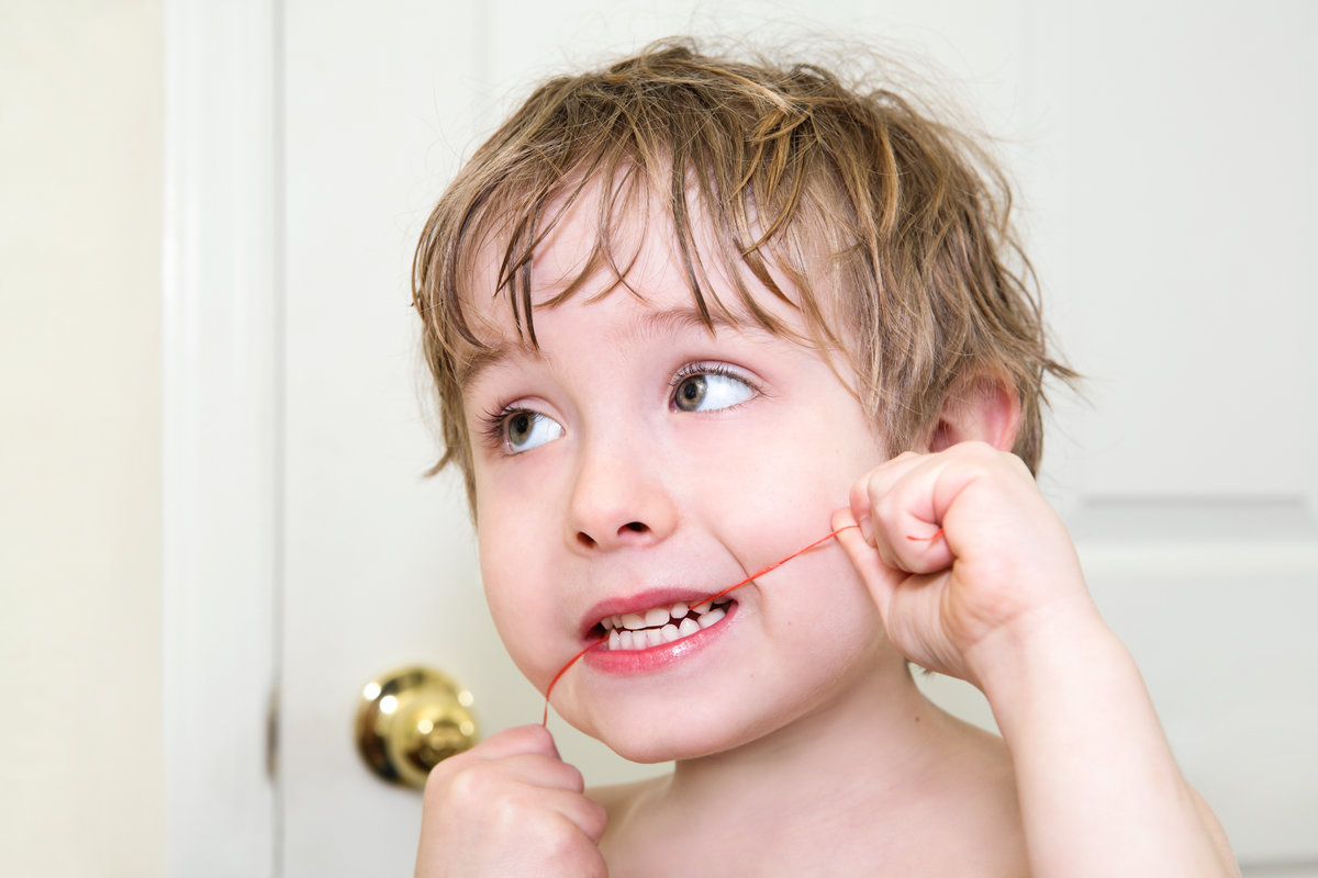 Young boy flossing his teeth, learning dental hygiene